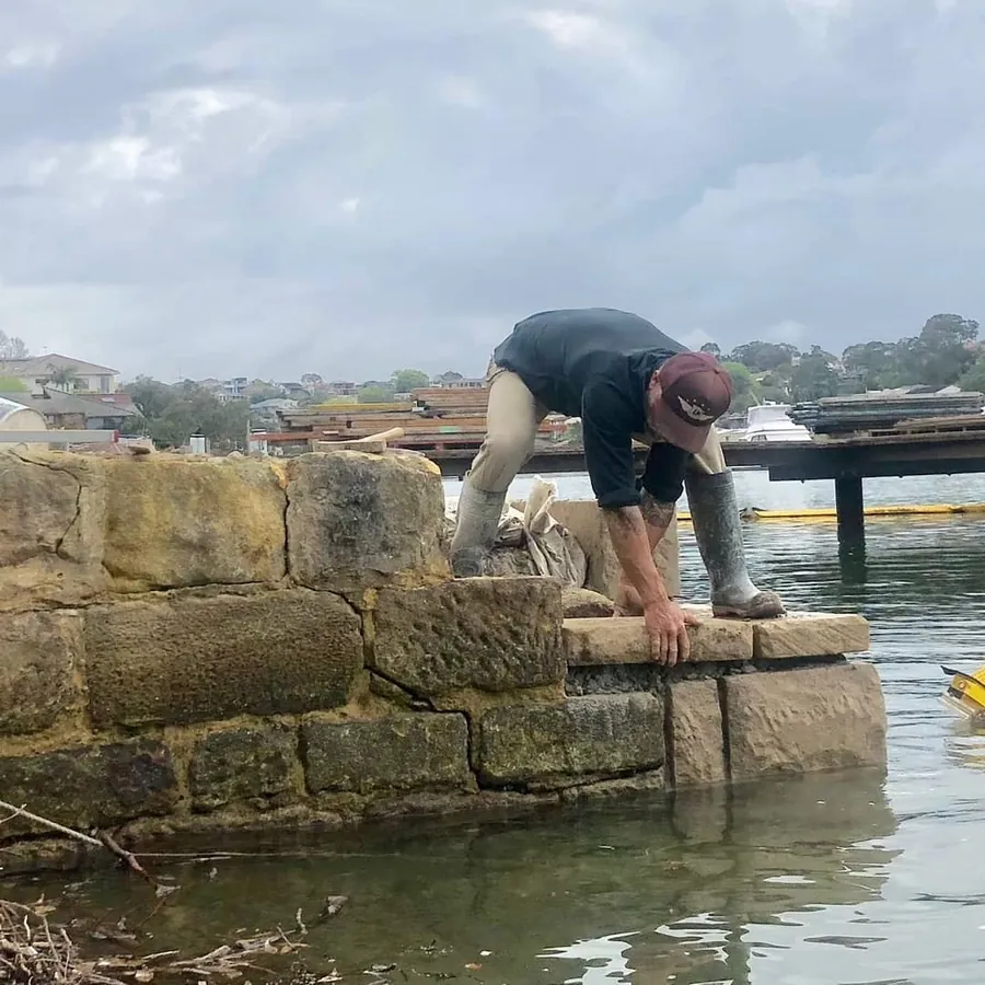 Stonemason repointing harbour sandstone seawall