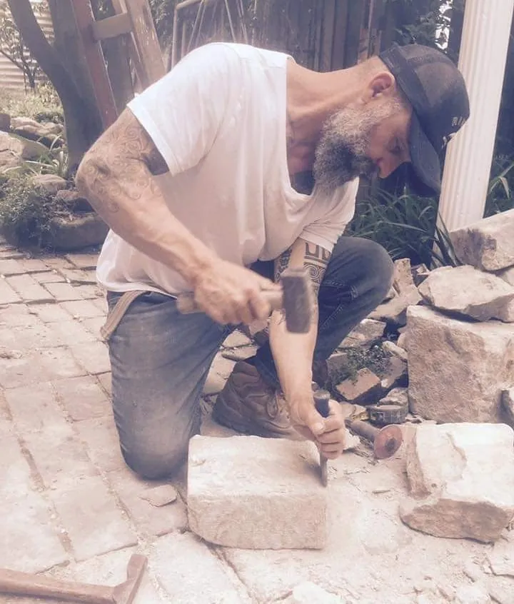 Minas Romanakis working sandstone by hand with a mallet and chisel