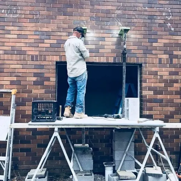 Worker installing steel beam above brick wall opening