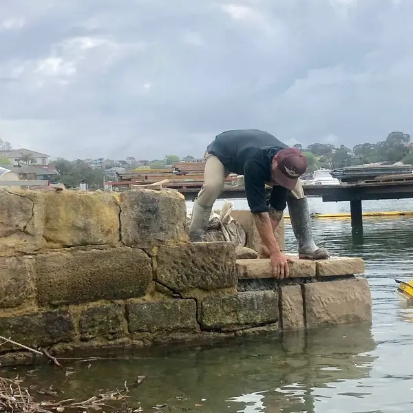 Stonemason repointing harbour sandstone seawall