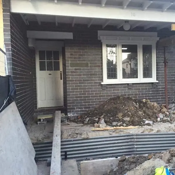 Residential brick home with foundation excavation underway