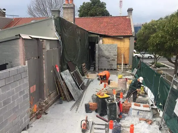 Block wall construction with cement mixer on urban site