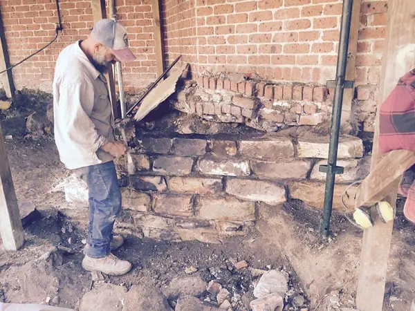 Worker levelling bricks on heritage wall repair