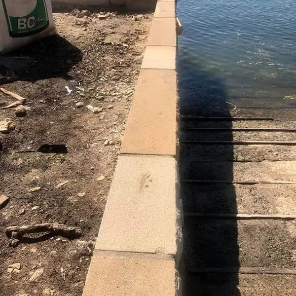 Sandstone seawall with harbour and boats in background