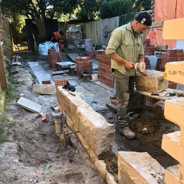 Stonemason laying sandstone blocks for retaining wall