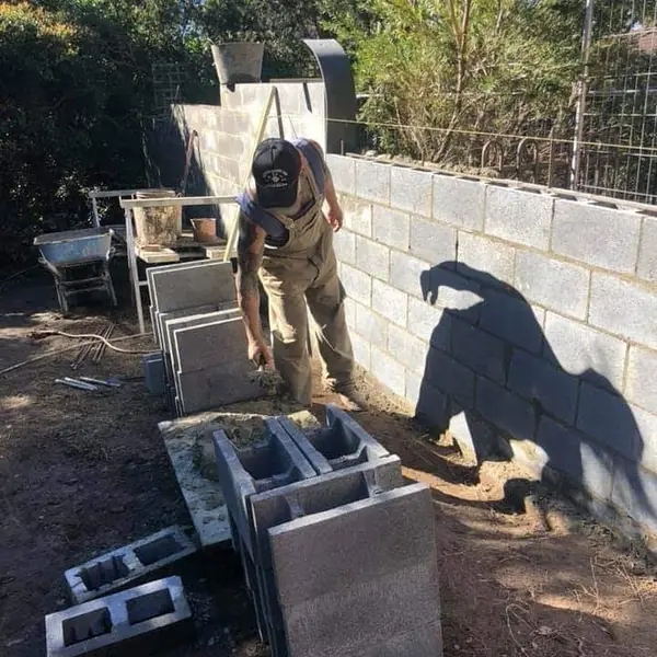 Worker building concrete block retaining wall on hillside