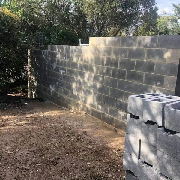Long rendered retaining wall alongside walkway