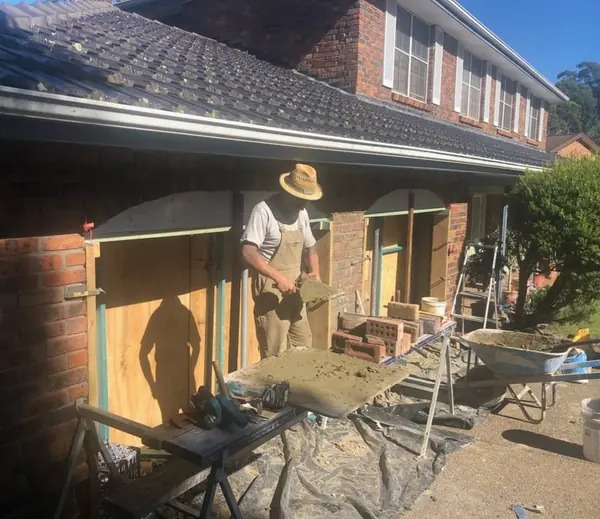 Worker mixing mortar on residential brick renovation