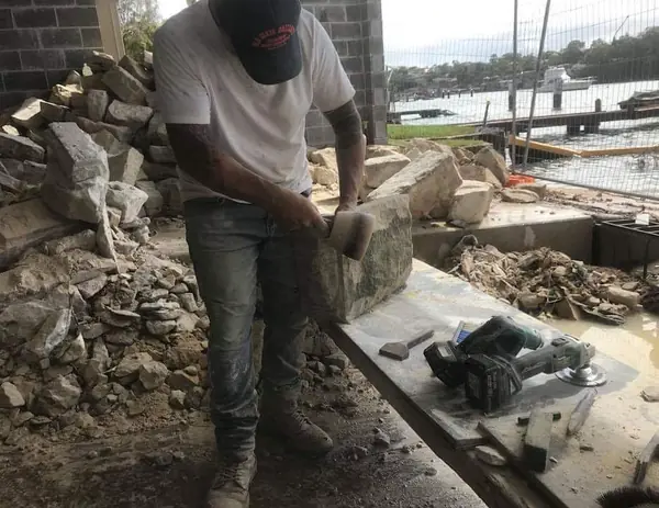 Stonemason handling sandstone blocks by harbour waterfront