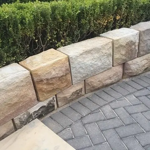 Stonemason working on sandstone seawall at dusk by harbour