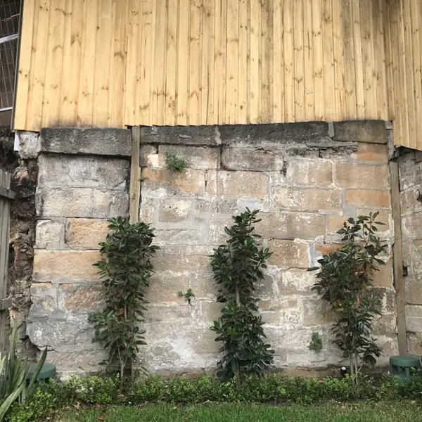 Weathered sandstone wall with timber hoarding above
