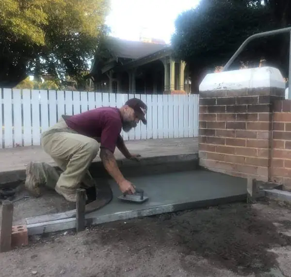 Minas trowelling fresh concrete pad at heritage property