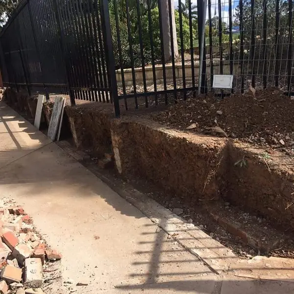 Brick retaining wall construction with iron fence above