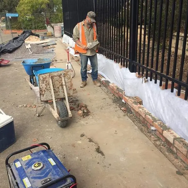 Completed brick boundary wall alongside iron railing