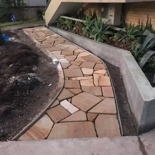 Sandstone crazy paving pathway with concrete retaining wall