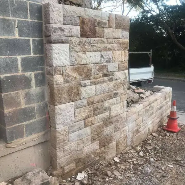 Sandstone cladding being applied to concrete block wall