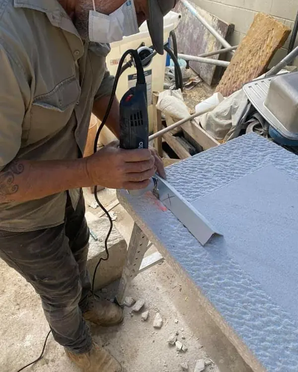 Stonemason using power tool to texture sandstone slab