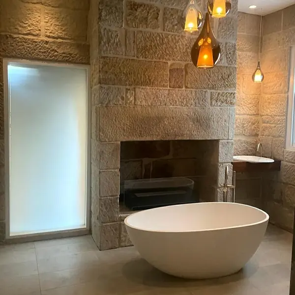 Luxury sandstone bathroom with freestanding bath and fireplace