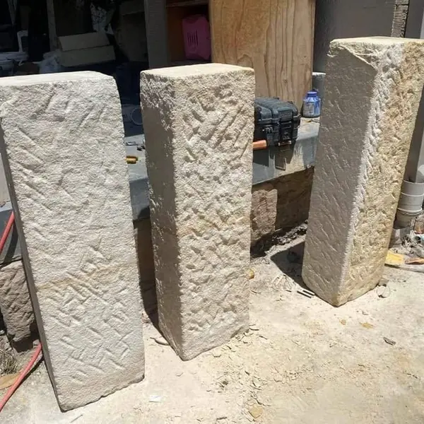 Hand-carved sandstone posts with textured finish in workshop