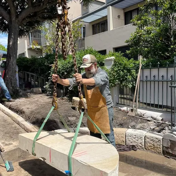 Workers positioning large sandstone block with lifting gear